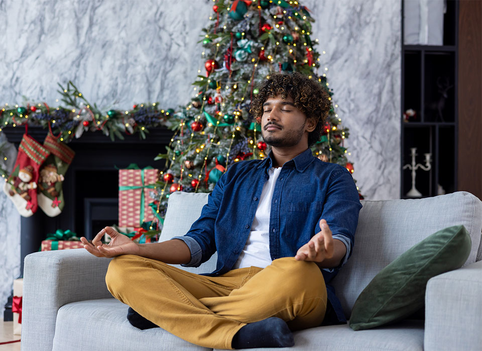 man practicing mindfulness, meditating by Christmas tree