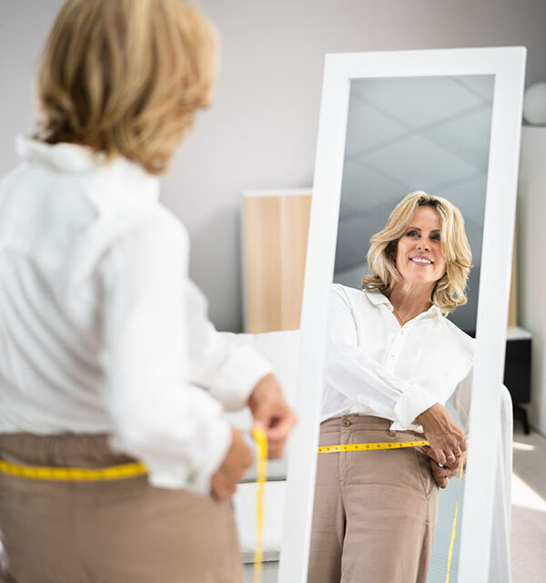 Smiling Slim Woman Looking At Her Reflection In Mirror