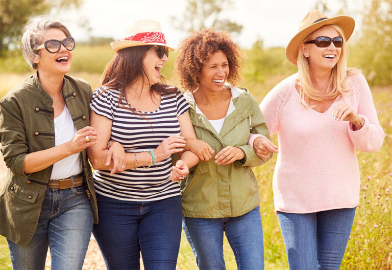 Group Of Mature Female Friends Walking Along Path Through Yurt Campsite