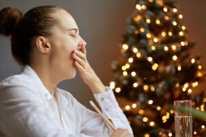 Woman yawning in front of a Christmas tree