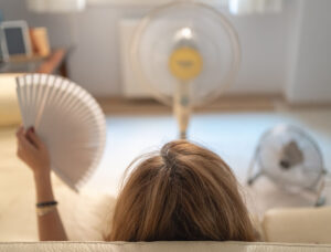 woman in menopause having a hot flash with lots of fans around her